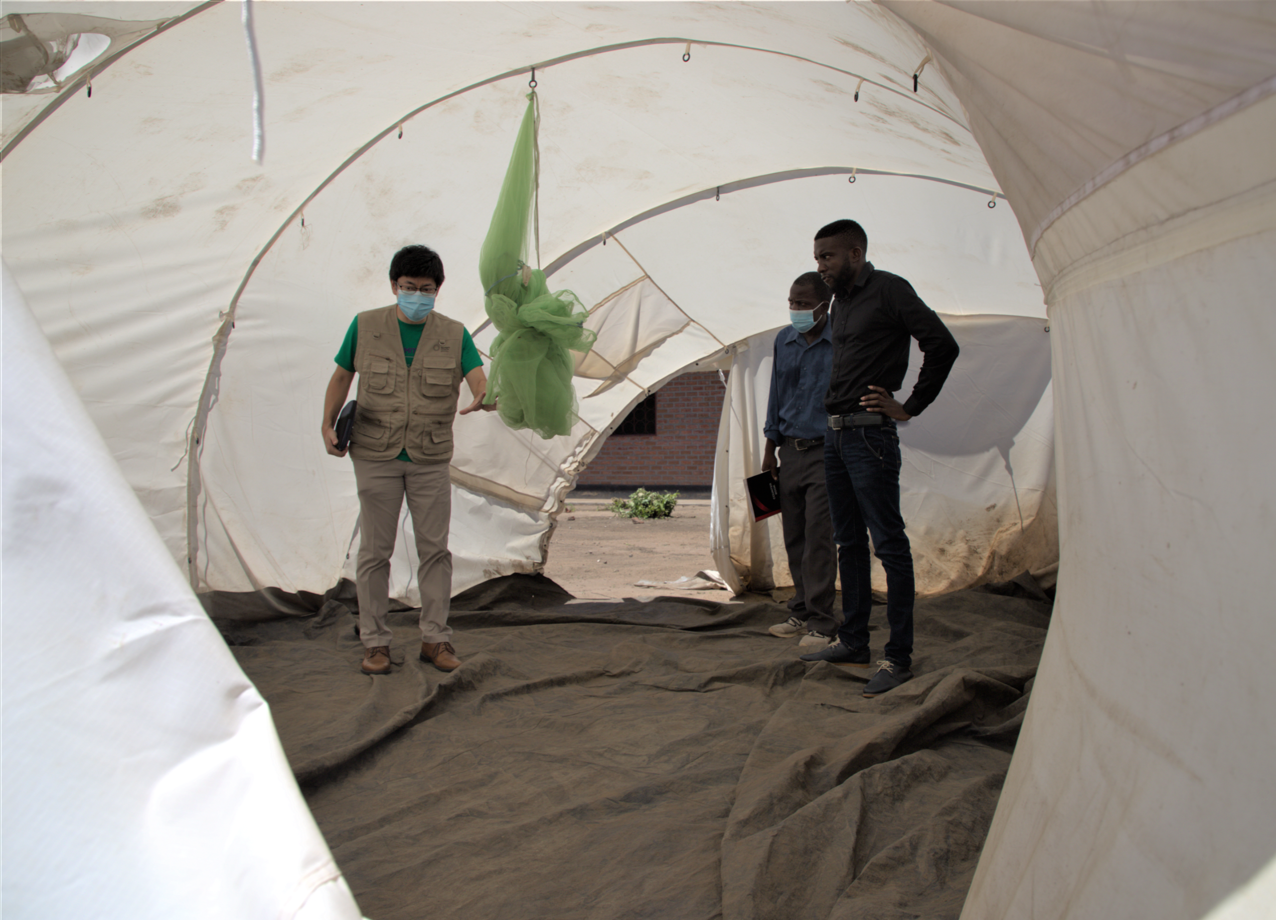 避難民のシェルターとして使用されているテント内部を視察するUNFPAマラウイ事務所副代表の渡部（左）と政府関係者。©UNFPA/Joseph Scott