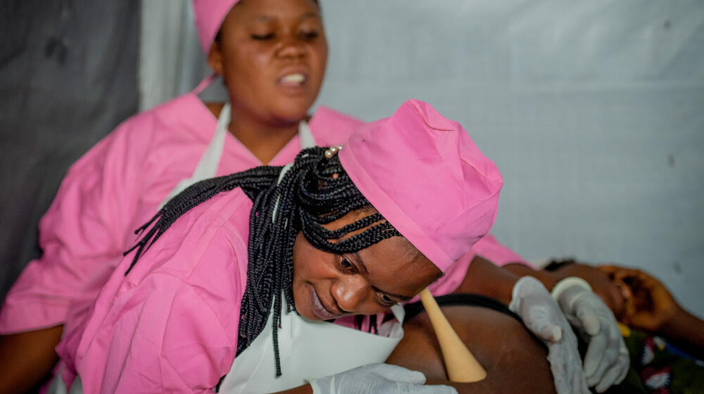 コンゴ民主共和国東部の北キヴ州ルサヨで、自宅から一時避難キャンプへの移動を余儀なくされた妊婦に、UNFPAの移動診療所で働く助産師が対応しました。© UNFPA/Junior Mayindu