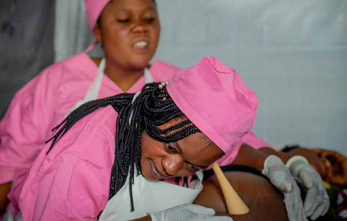 コンゴ民主共和国東部の北キブ州ルサヨで、自宅から一時避難キャンプへの移動を余儀なくされた妊婦に、UNFPAの移動診療所で働く助産師が対応しました。© UNFPA/Junior Mayindu