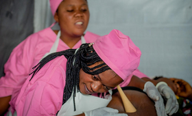 コンゴ民主共和国東部の北キブ州ルサヨで、自宅から一時避難キャンプへの移動を余儀なくされた妊婦に、UNFPAの移動診療所で働く助産師が対応しました。© UNFPA/Junior Mayindu